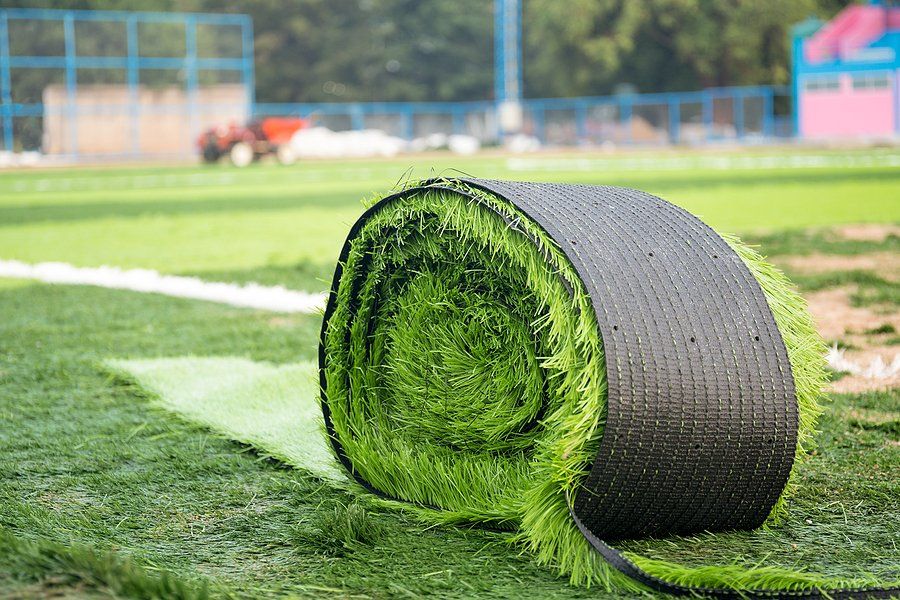 Huge roll of fake grass being installed on a school field