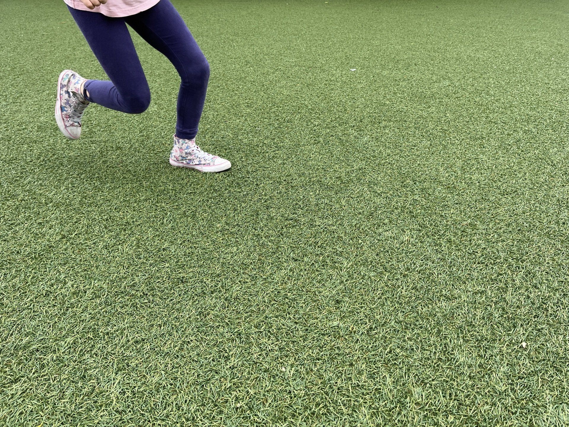 running kid's feet on artificial lawn, playing in yard