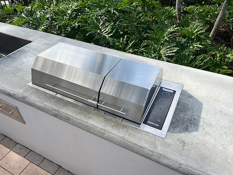 Outdoor kitchen setup featuring a concrete countertop, electric grill, and stainless steel sink