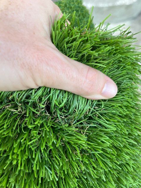 a person holding a synthetic turf for quality control