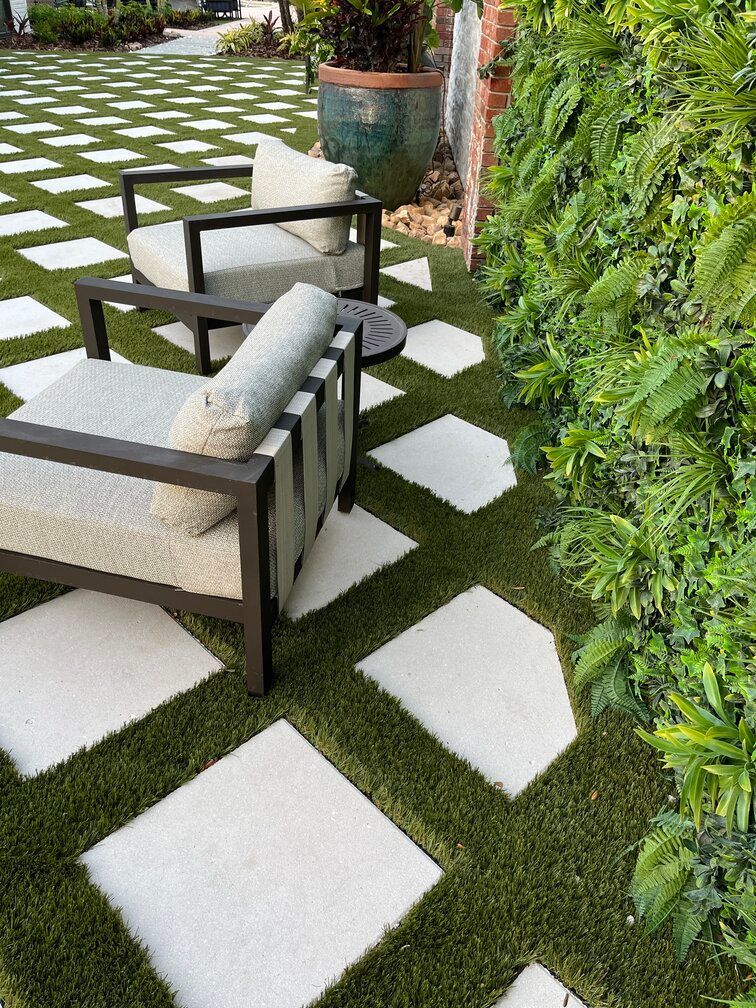 diamond pavers along green wall with patio furniture on astroturf