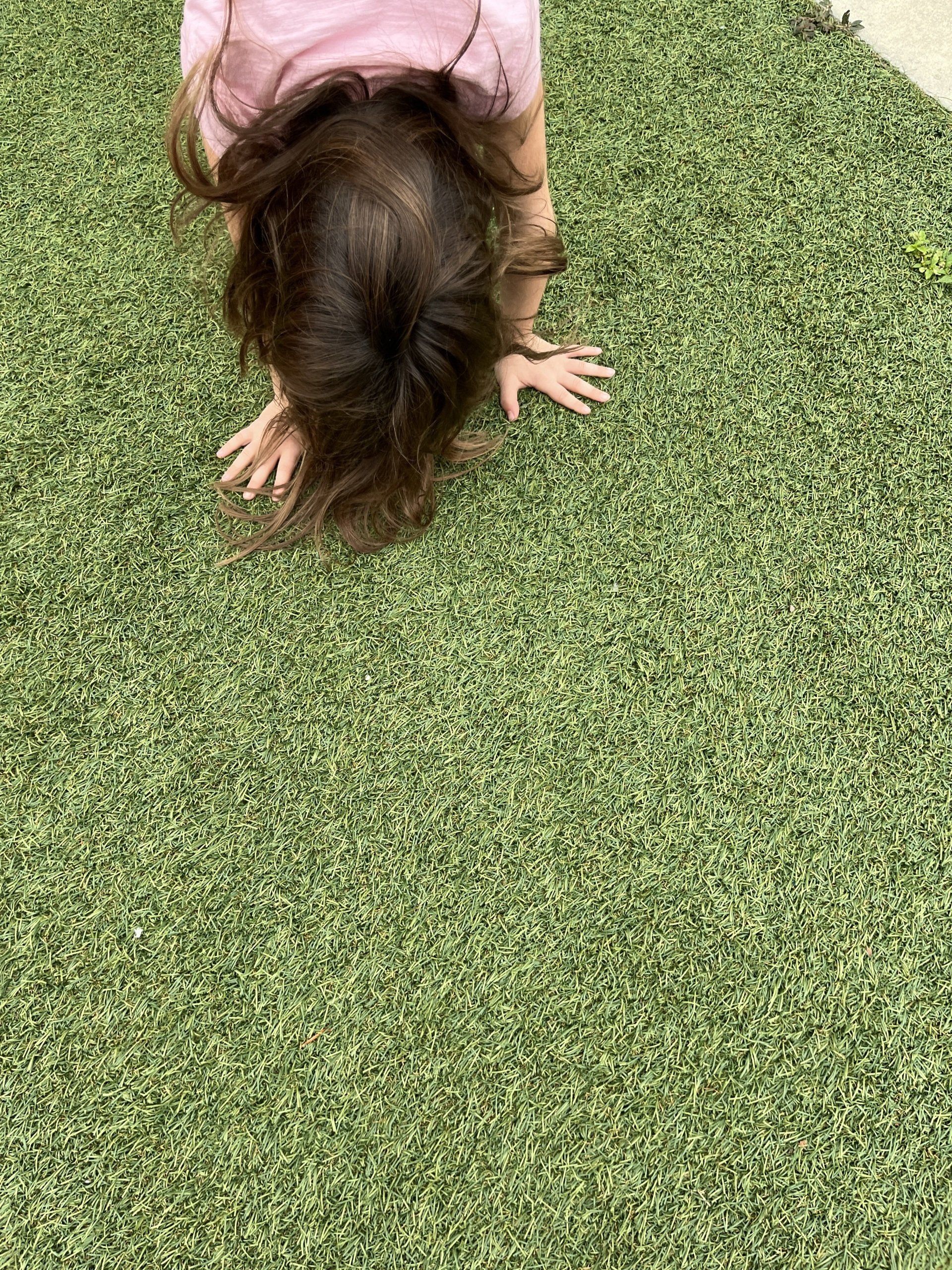 kid doing handstand on green fake grass