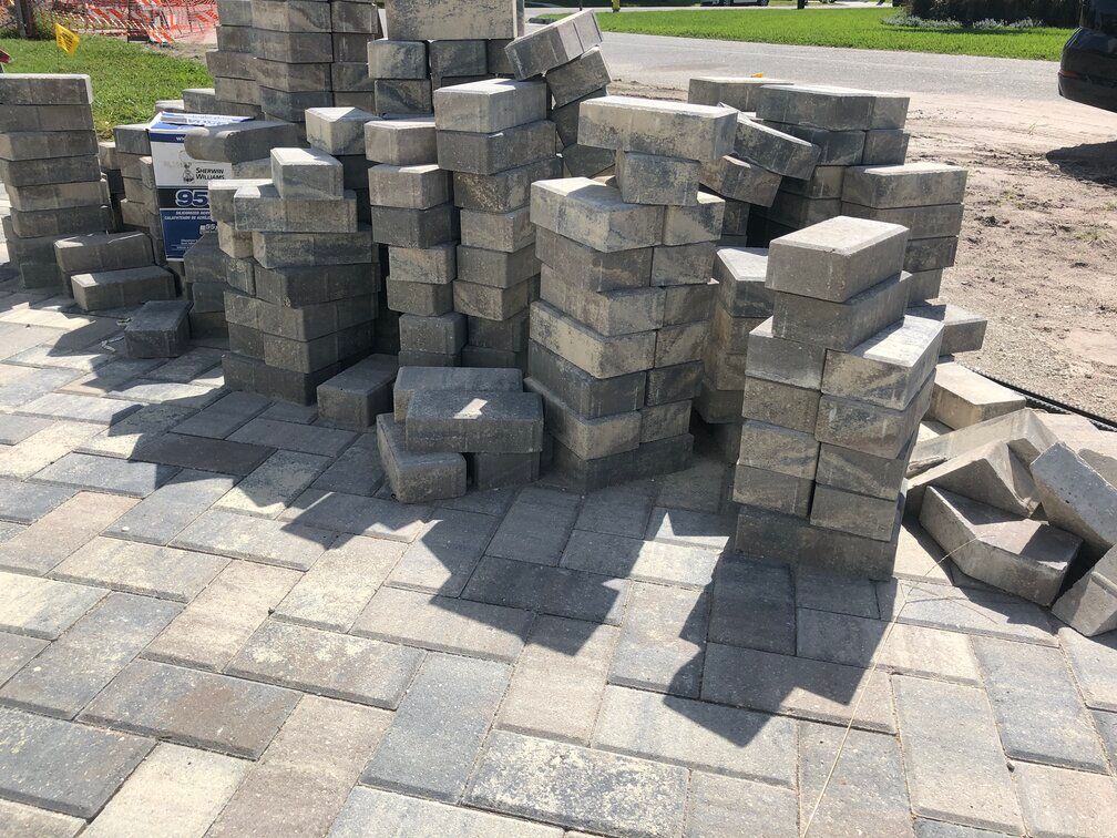 after delivery, a stack of pavers sits on a new driveway mid-installation