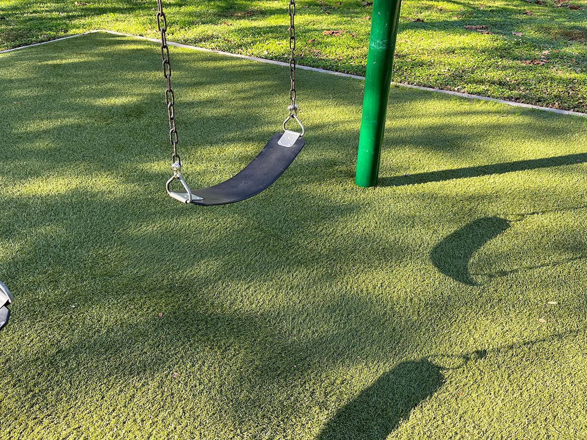 artificial playground grass installed beneath swings for safety and cushion