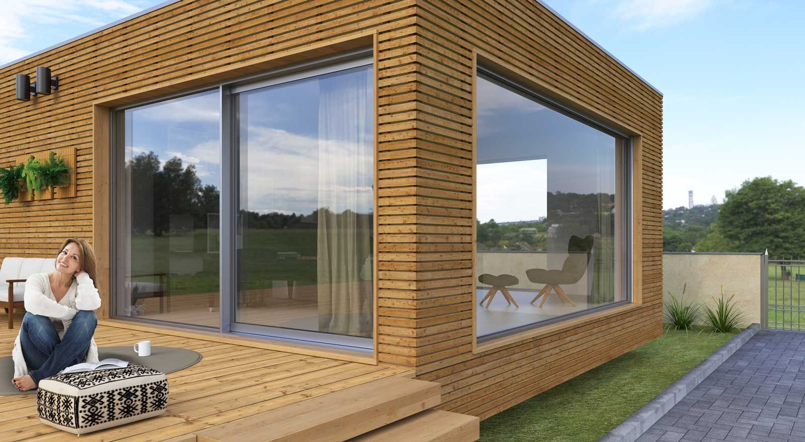 Una donna è seduta su una terrazza di legno davanti a una casa.