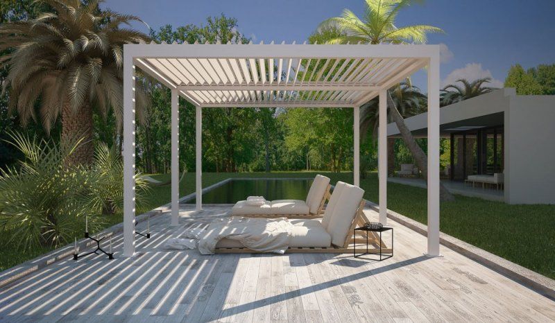 Un pergolato bianco è posto sopra una terrazza in legno accanto a una piscina.
