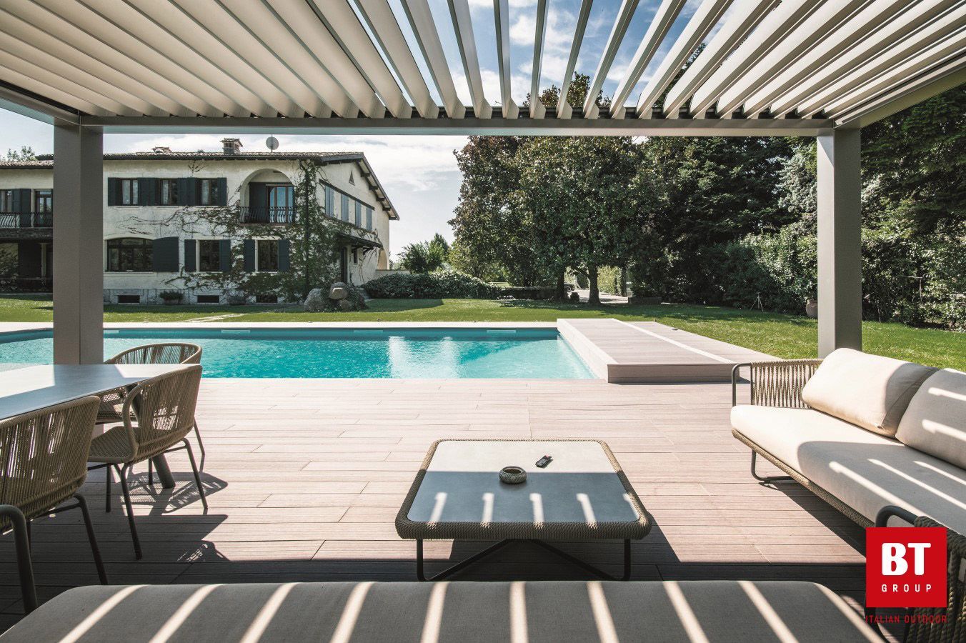 Un patio con pergolato e piscina sullo sfondo.