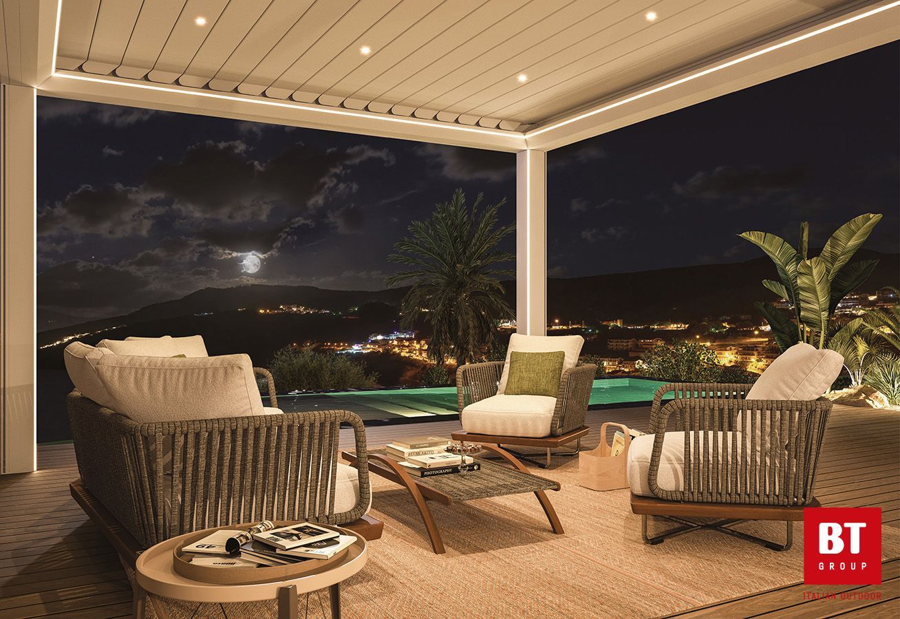 Un patio con sedie, un tavolo e un pergolato di notte.