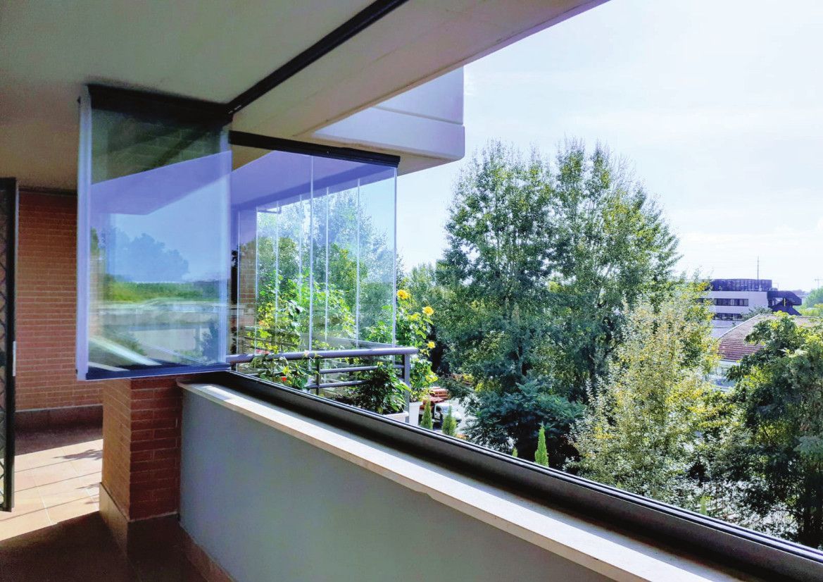 Un balcone con tante finestre e alberi sullo sfondo.