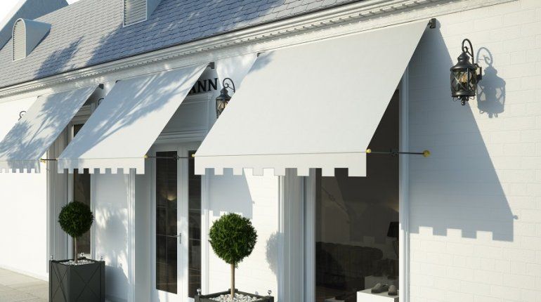 Una casa bianca con una tenda da sole bianca sopra la porta d'ingresso.