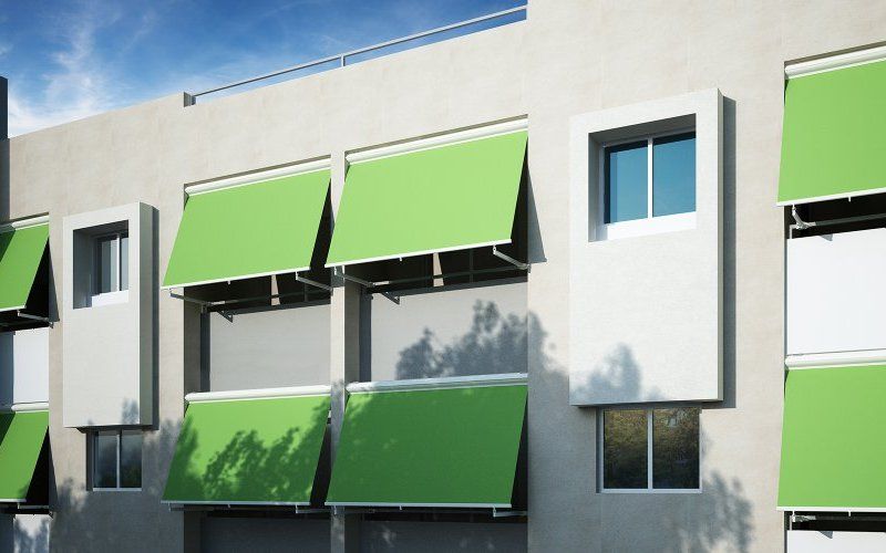 Un edificio con tende da sole verdi alle finestre