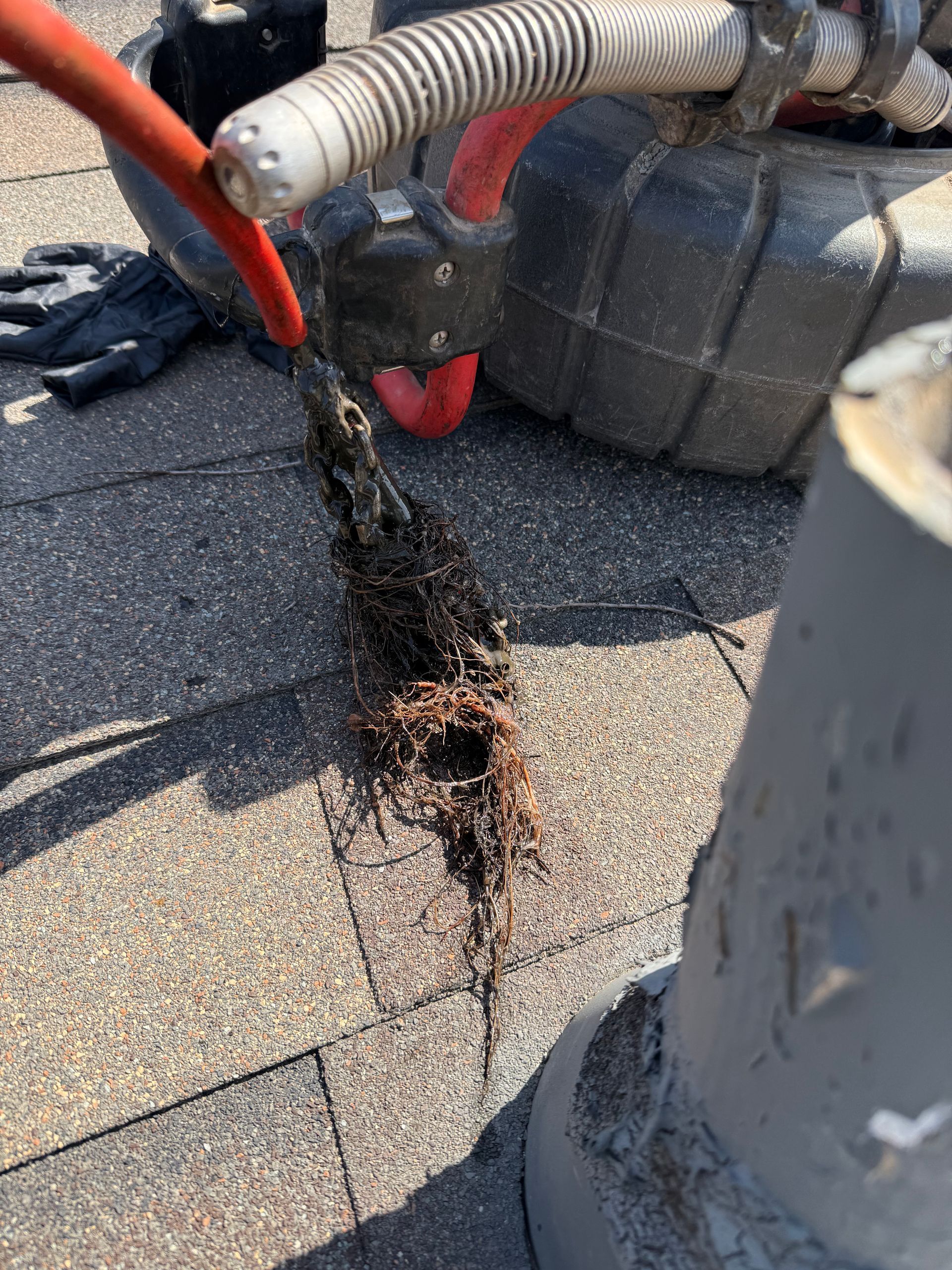 A hose is being used to remove roots from a pipe on a roof.
