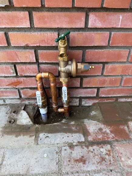 A copper pipe is attached to a brick wall.