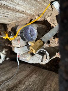 A close up of a pressure gauge attached to a pipe.