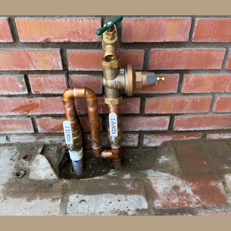 A hole in the wall with copper pipes coming out of it.