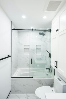 A bathroom with a tub , toilet , sink and shower.