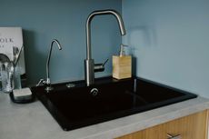 A kitchen sink with two faucets and a soap dispenser on the counter.