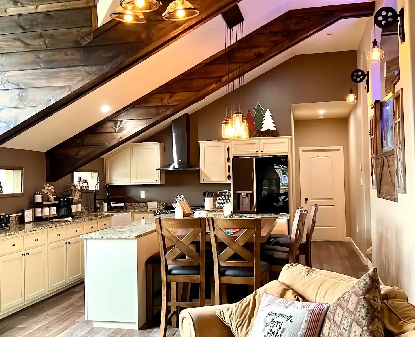 A living room with a couch , chairs , a table and a kitchen.