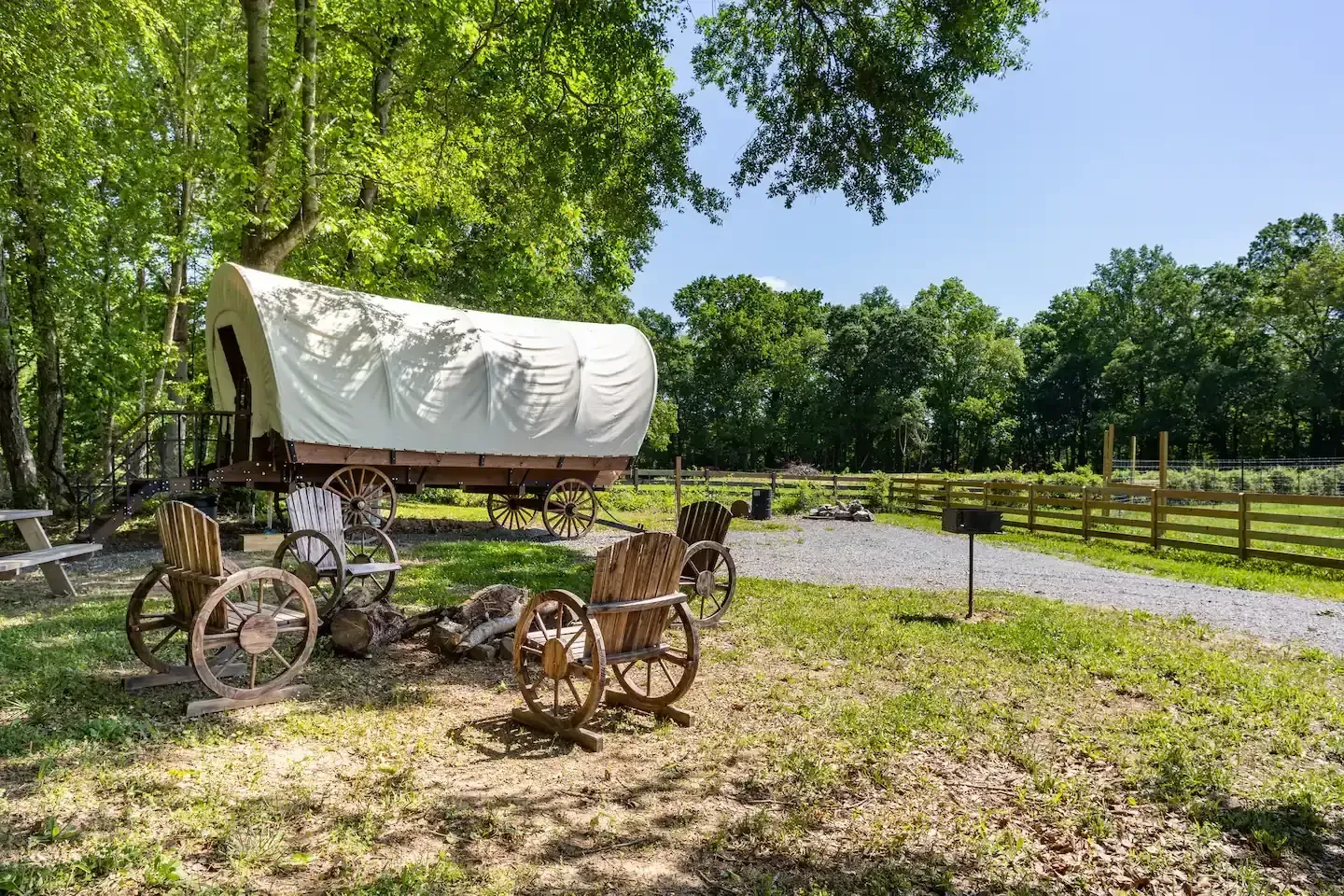 A covered wagon is parked in the middle of a grassy field.