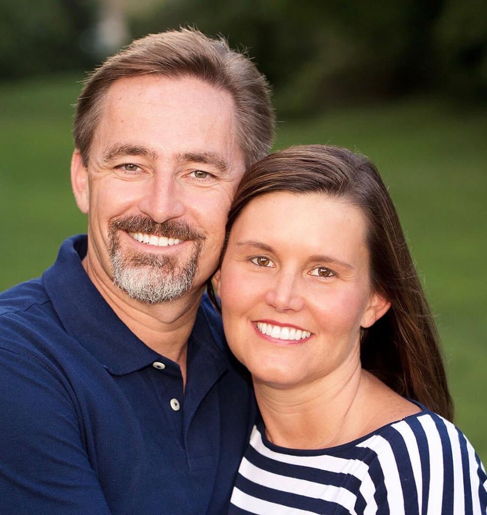 A man and a woman are posing for a picture and smiling for the camera.