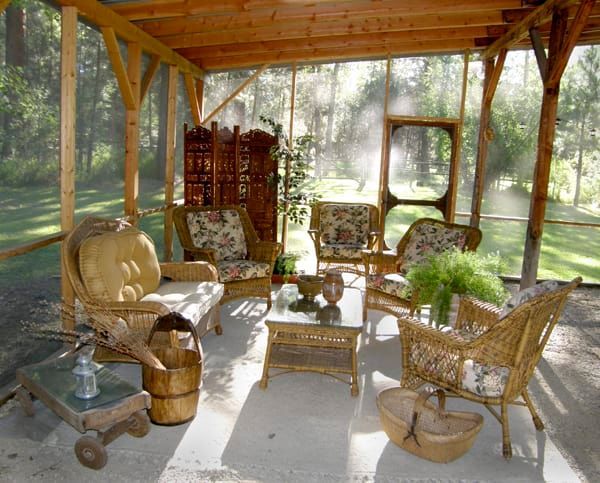 A screened in porch with wicker furniture and a table
