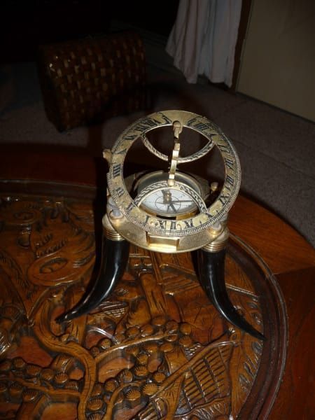 A clock with roman numerals is on a table