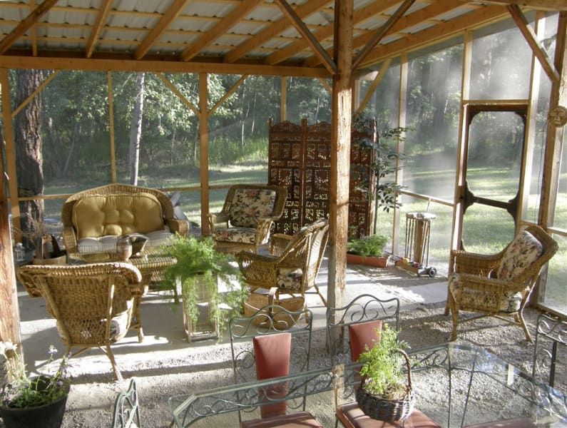A screened in porch with wicker furniture and a table