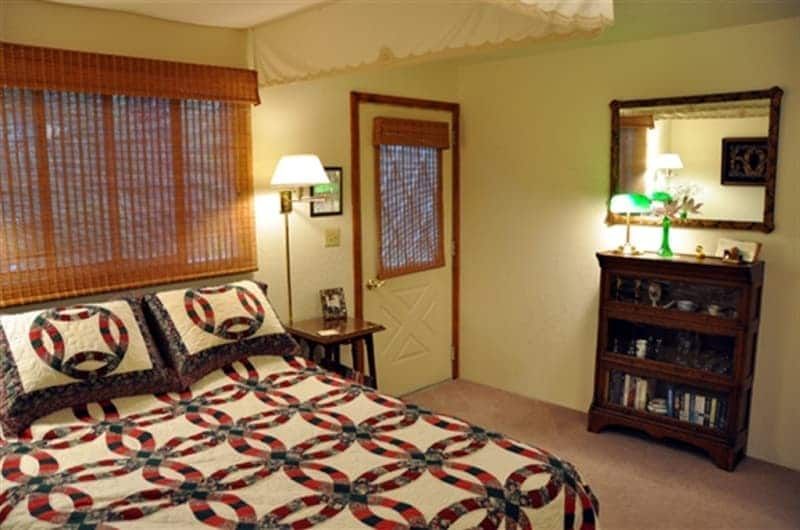 A bedroom with a quilted bed and a mirror