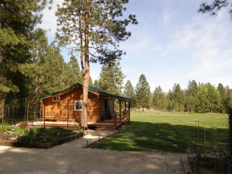 A small log cabin in the middle of a grassy field