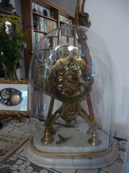 A clock is under a glass dome in a room