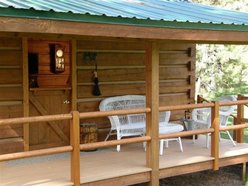A log cabin with a porch with a bench and chairs