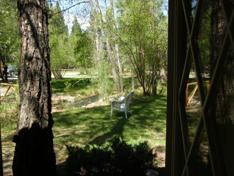 A view of a park through a window with a chair in the foreground