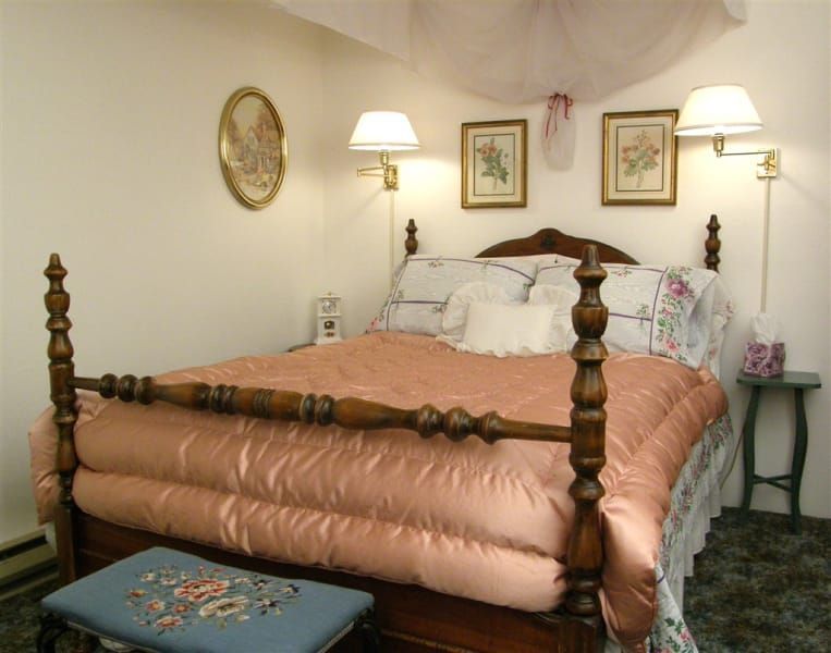 A bedroom with a canopy bed and two lamps