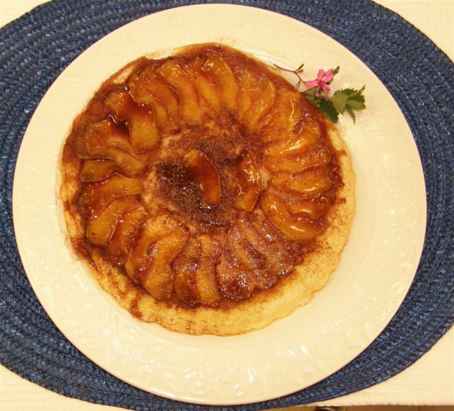 A white plate topped with an upside down apple pie