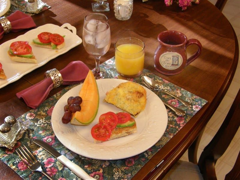 A table with a plate of food and a glass of orange juice