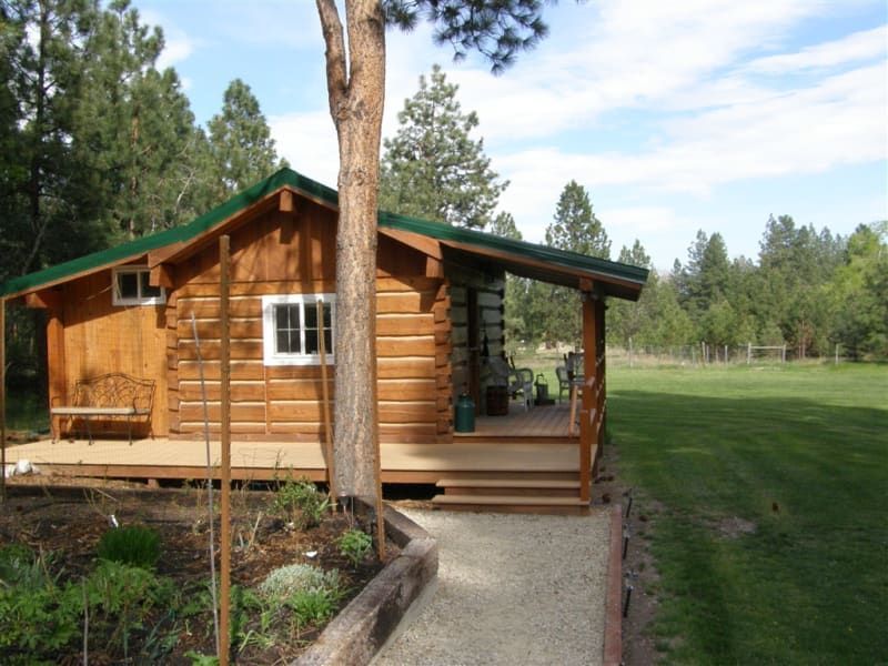 A small log cabin with a green roof and a porch