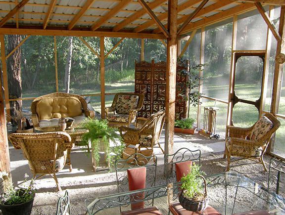 A screened in porch with wicker furniture and plants
