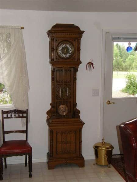 A grandfather clock in a living room next to a chair