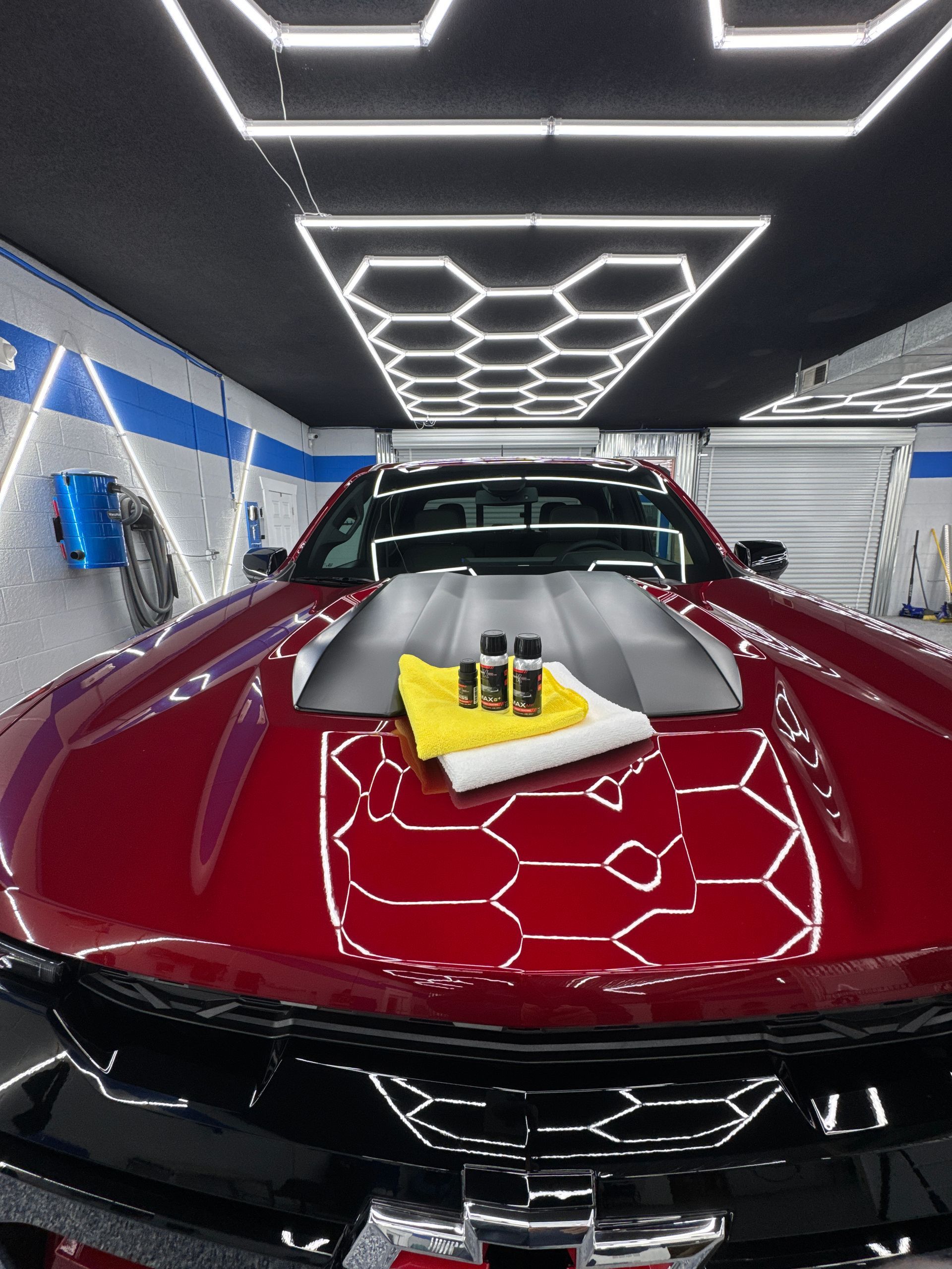 A man is washing a car with a red sponge.
