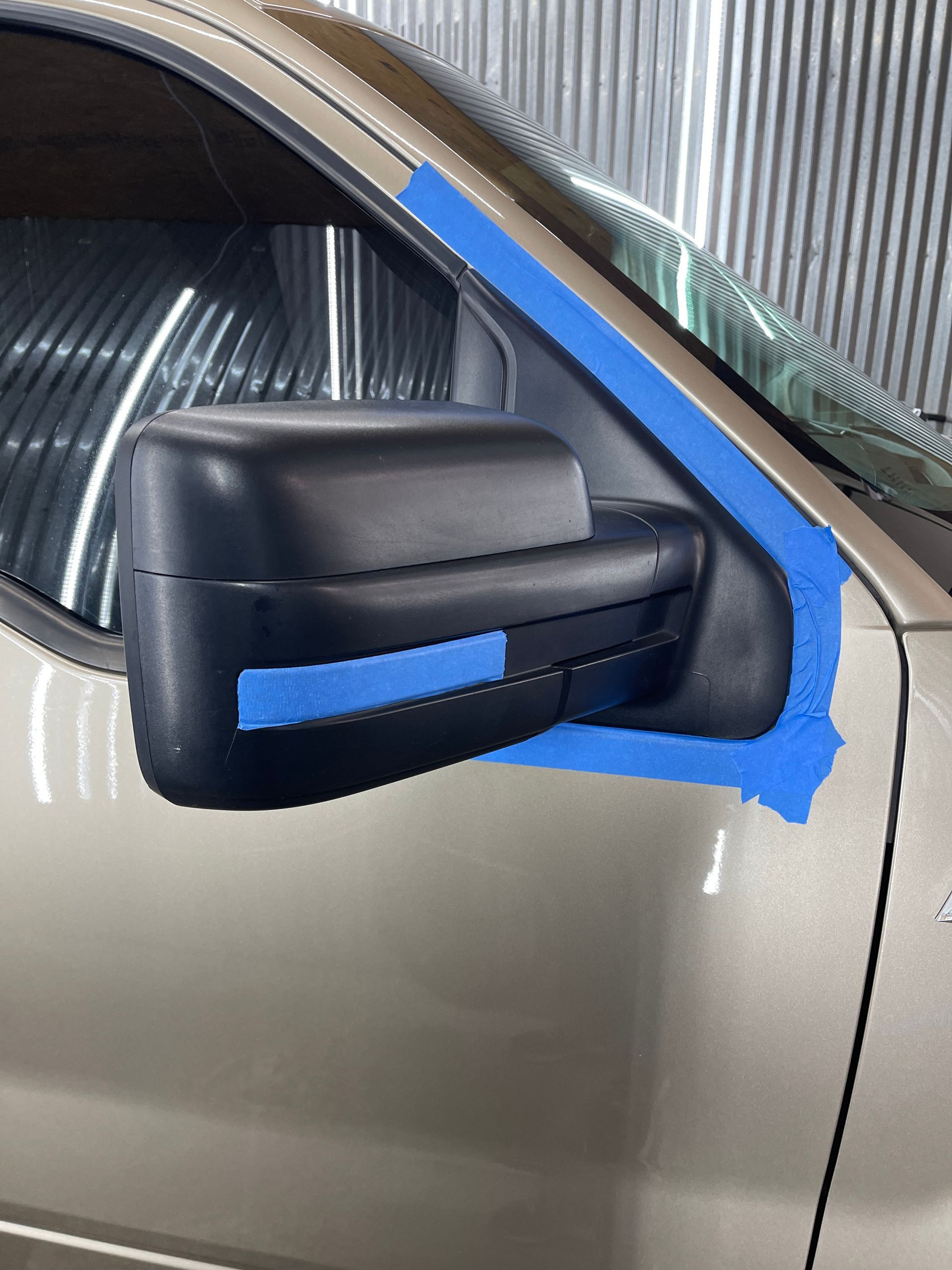 A close up of a car with blue tape on the side mirror