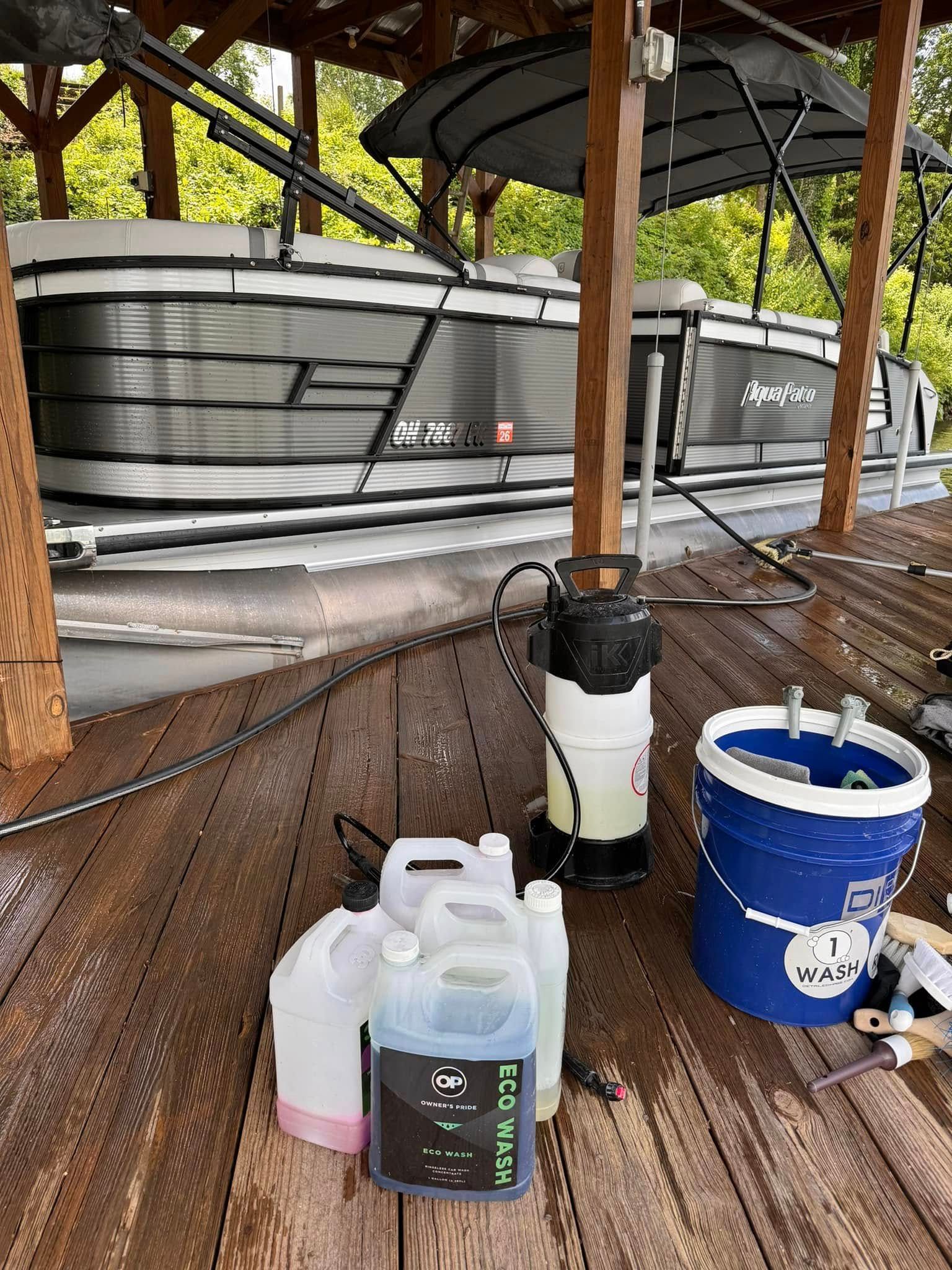 A pontoon boat docked at a wooden pier, cleaning supplies nearby.