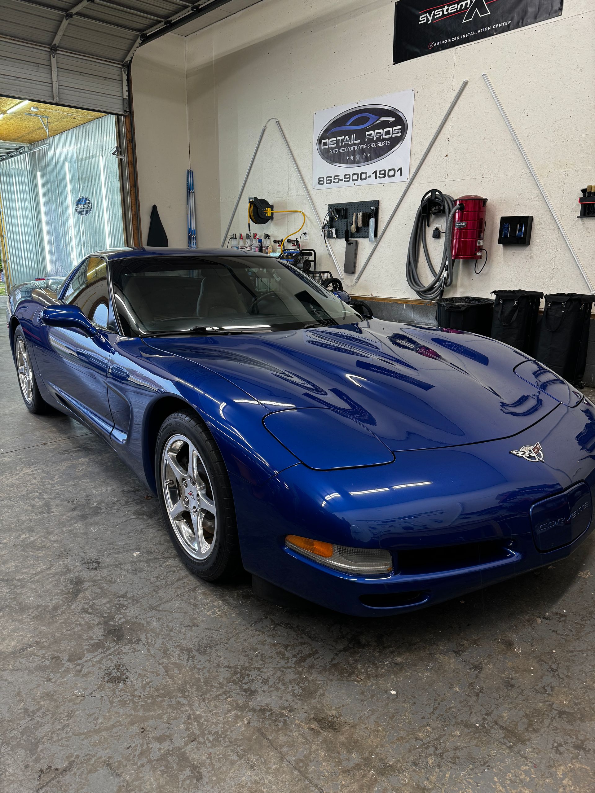 A blue corvette is parked in a garage.