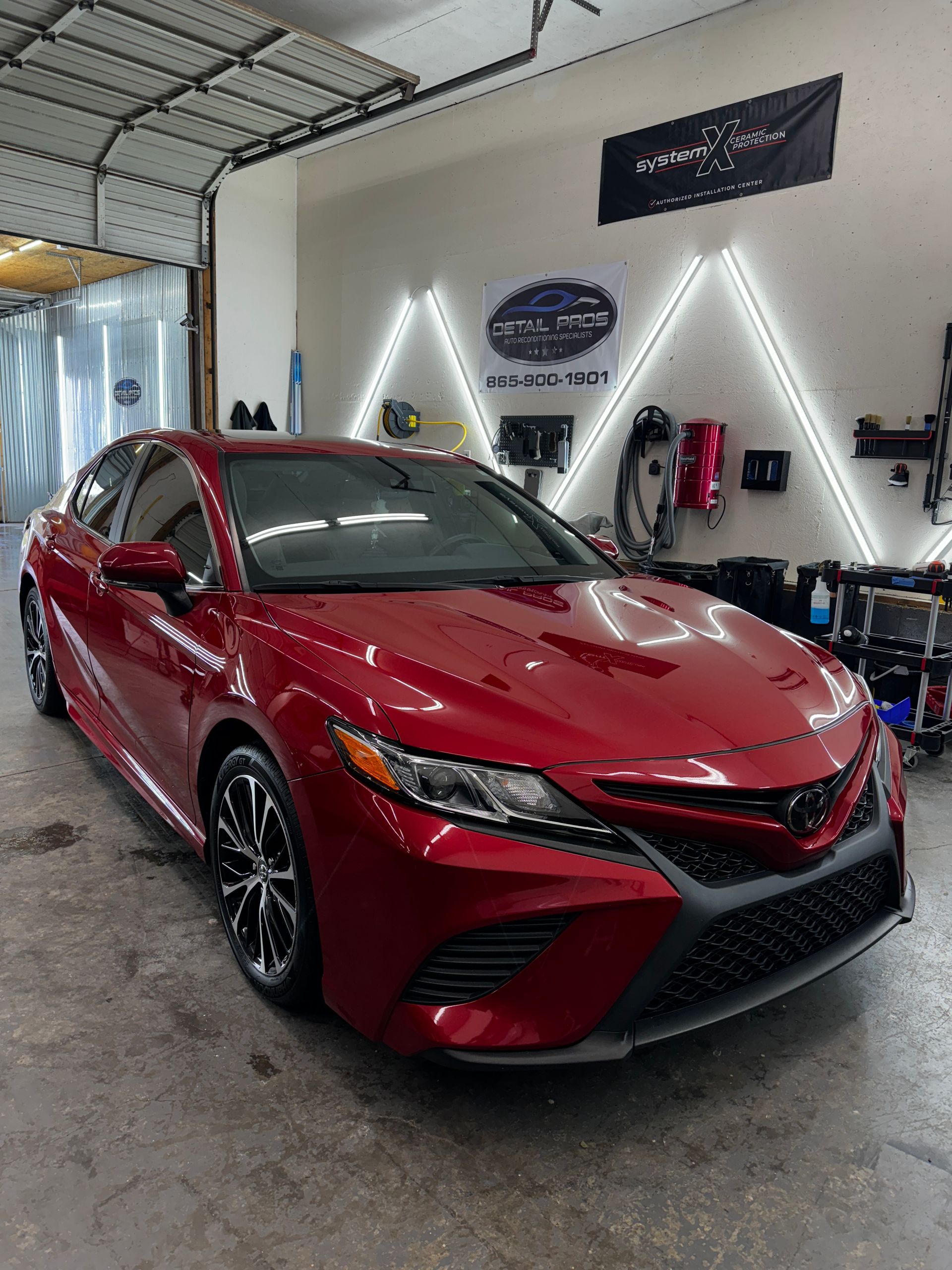 A red toyota camry is parked in a garage.