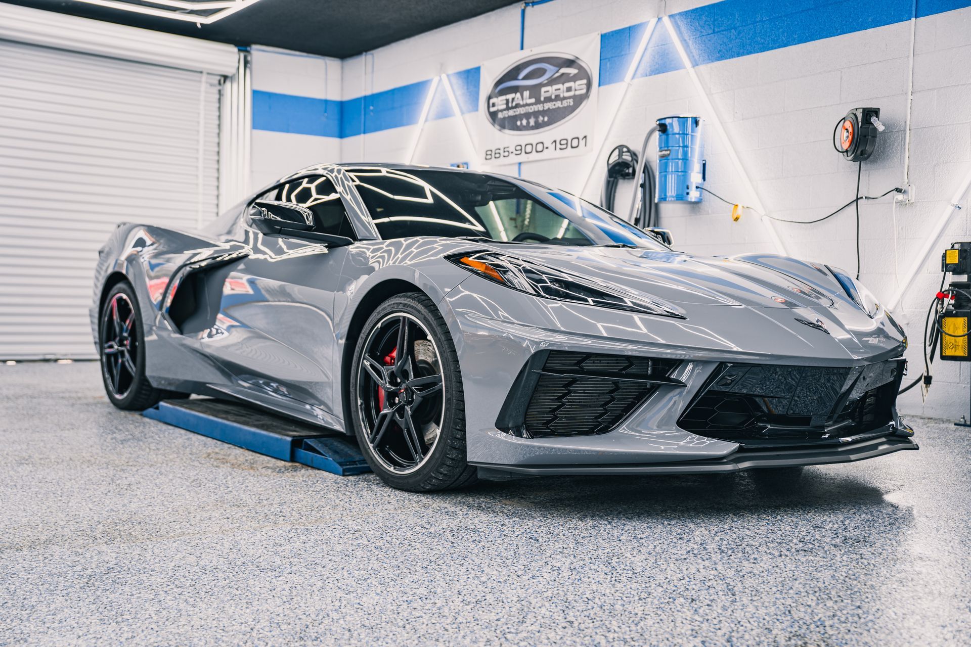 Gray Chevrolet Corvette sports car inside a car detailing shop, with red brake calipers.