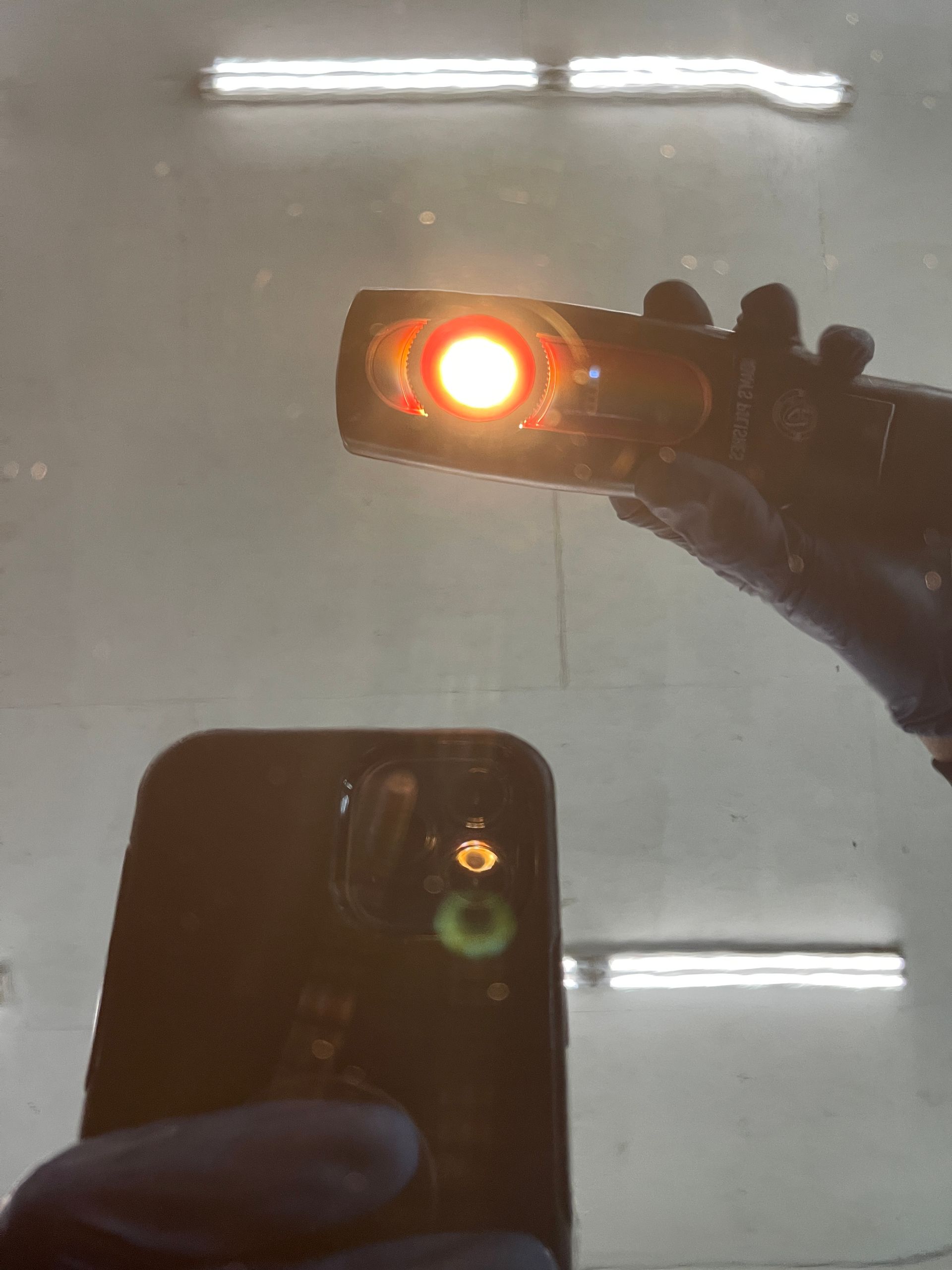 A person is holding a flashlight over a cell phone