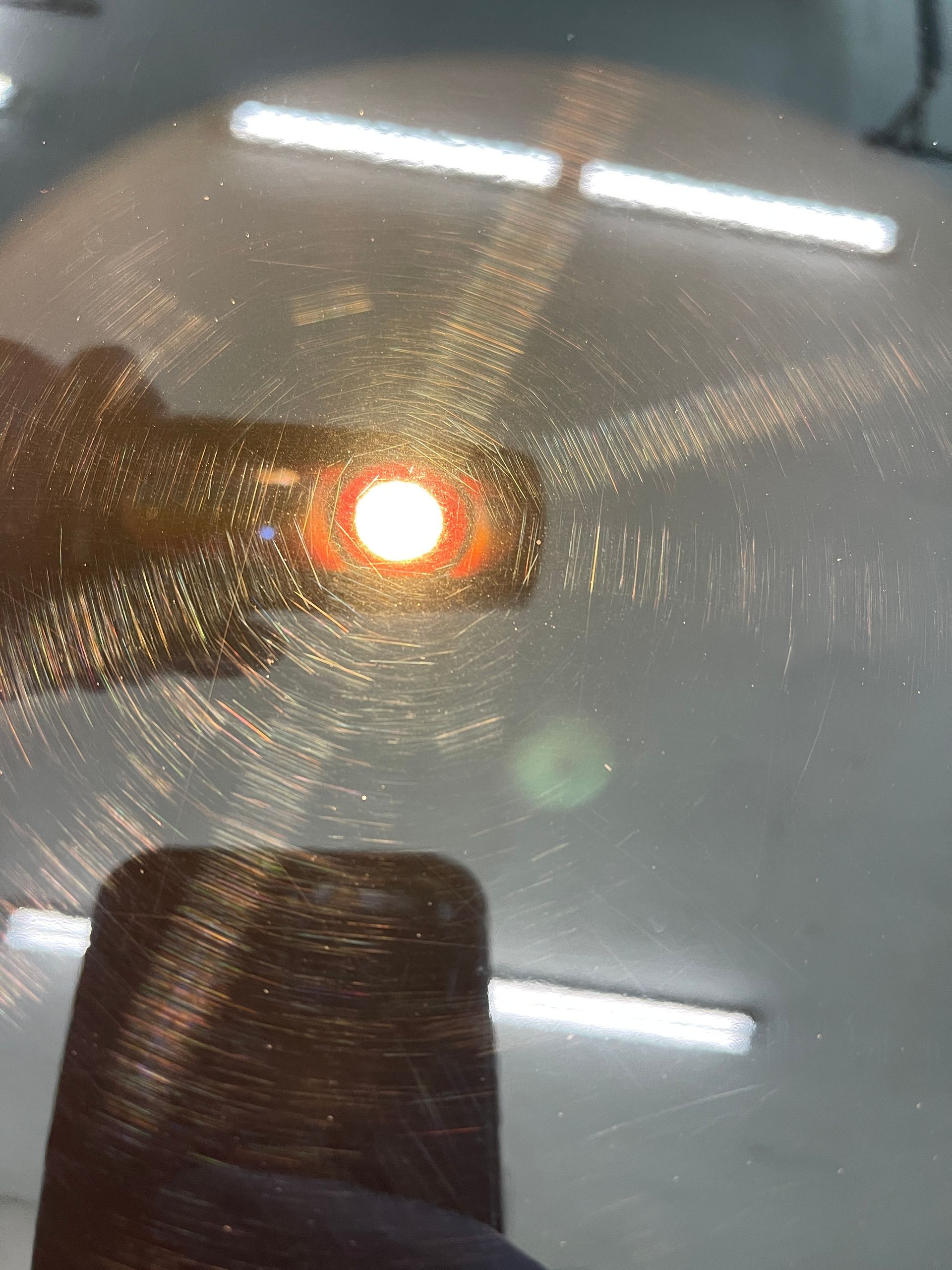 A close up of a car windshield with a red light reflected in it.
