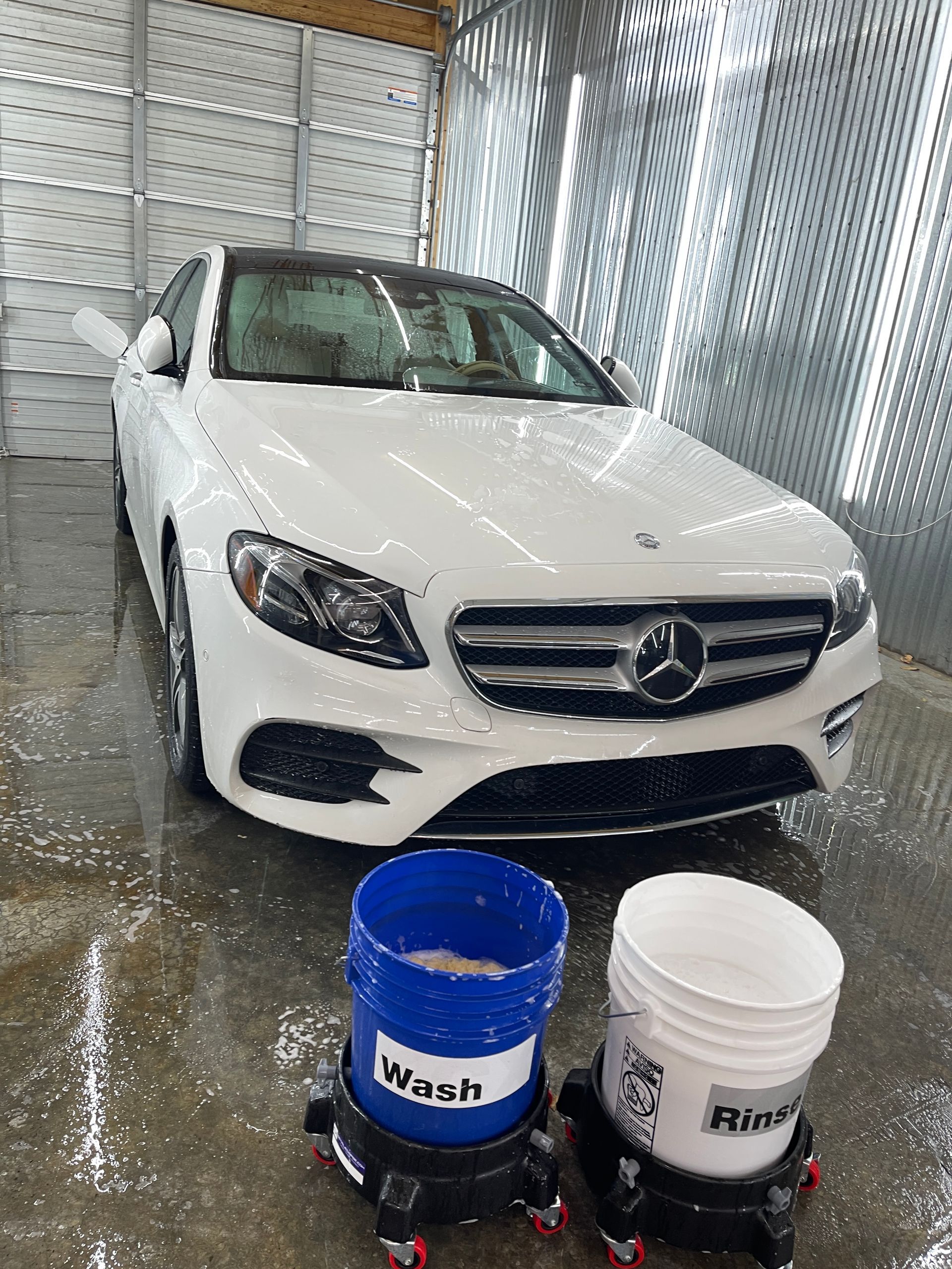 A white mercedes benz is being washed in a car wash.