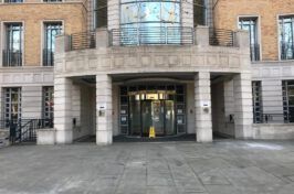 A large building with a yellow wet floor sign in front of it.