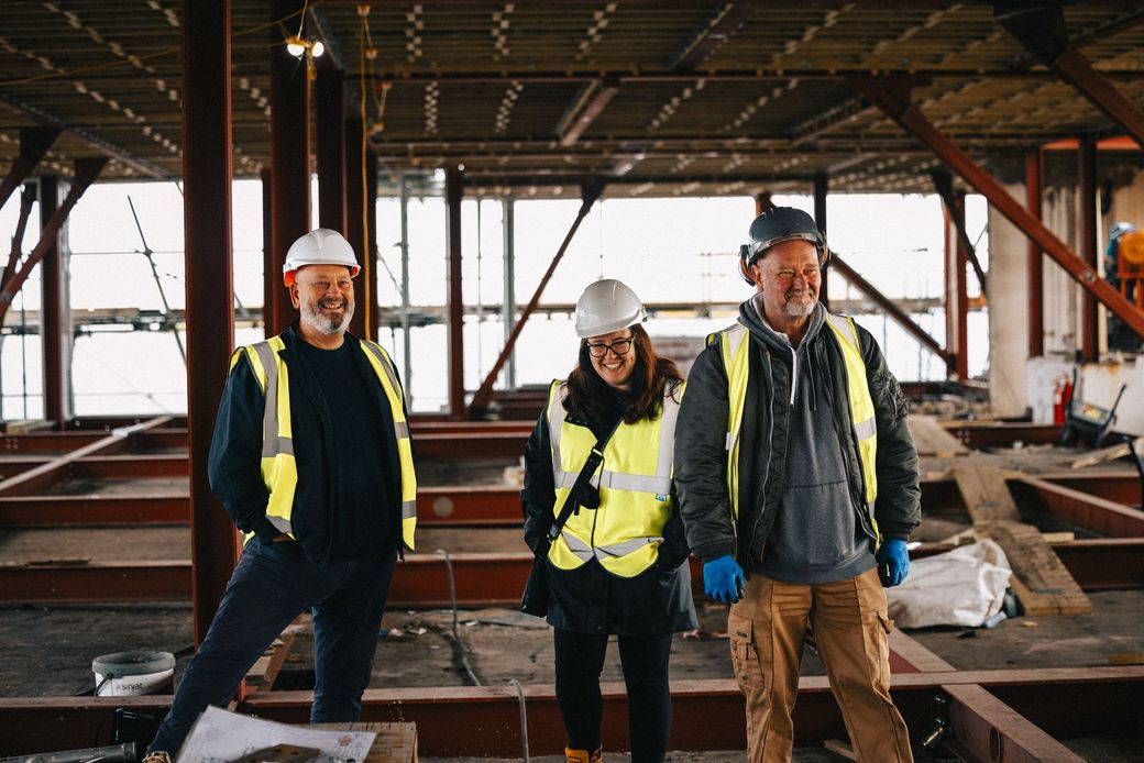 A group of construction workers are standing in a building under construction.