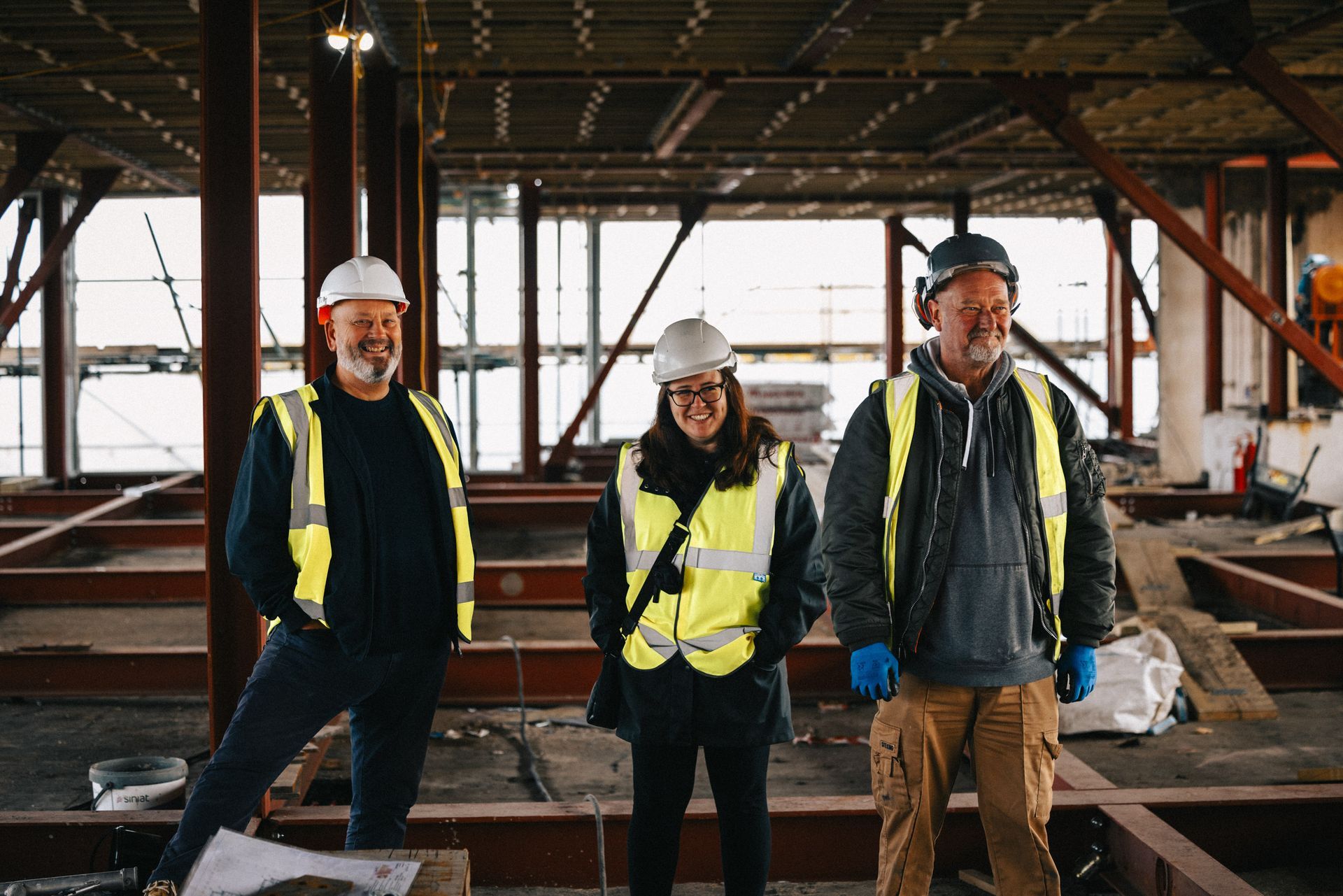 A group of construction workers are standing next to each other in a building under construction.